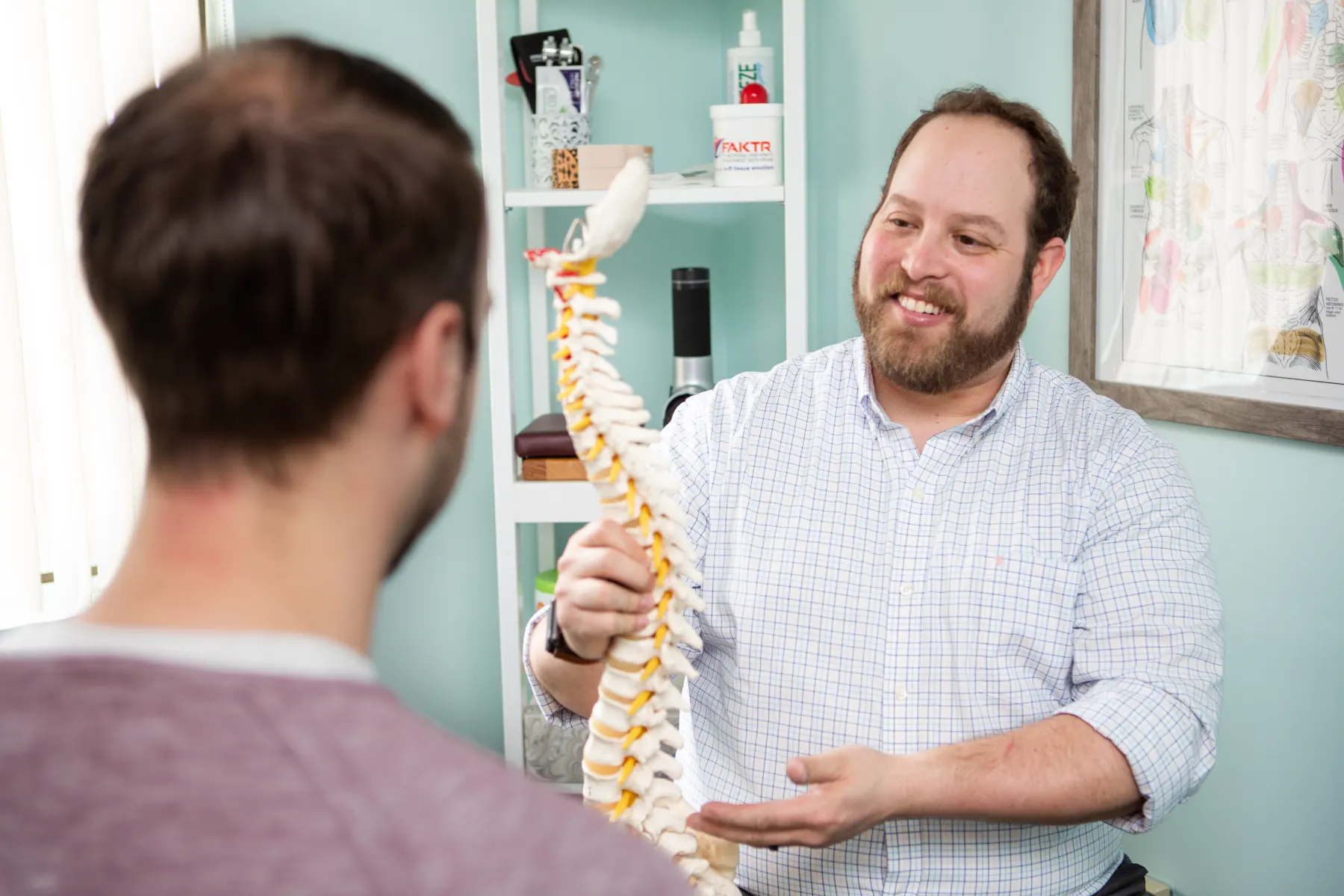 Dr. Scott Rosner explaining the spine to a patient with an anatomical model